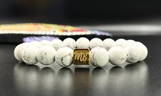 Discovered in Nova Scotia, "White Buffalo" stone has great calming properties. It will give you the gift of wisdom and enlightenment. Howlite's unique pourous texture feels great against the skin. Memory, Patience, Knowledge 10mm beads accented by a highly polished gold finish stainless steel logo bead Marble Agate Jewelry As A Gift, White Holistic Jewelry For Gifts, Marble Agate Jewelry Gift, White Polished Beads Jewelry For Healing, Handmade White Beaded Bracelets, White 8mm Beads Jewelry As Gift, White Jewelry With 8mm Beads As Gift, White Jewelry With 8mm Beads For Gift, Everyday White Polished Beads Jewelry