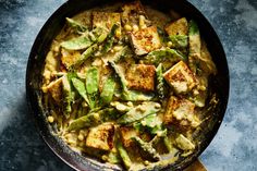 a skillet filled with tofu and asparagus on top of a table