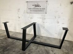 two black metal tables sitting in front of a white wall with a sign on it