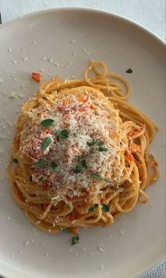 a white plate topped with pasta covered in sauce and parmesan cheese sprinkled on top