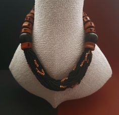 An opulent Necklace with fish vertebrate and ebony beads.Pierced fish vertrebrate are allready known as jewelry from the neolithic era. Rocailles beads made of glass and clay are inserted in the center. Size of ebony bead: 23 mm Length: 52 cm or 20,47 inch Brown Jewelry With Black Beads For Gift, Adjustable Brown Necklace With Black Beads, Gift Brown Jewelry With Black Beads, Artisan Necklace With Brown And Black Beads, Black Multi-strand Wooden Bead Necklaces, Black Multi-strand Wooden Beaded Necklaces, Traditional Brown Jewelry With Black Beads, Artisan Brown Spacer Beads, Unique Adjustable Black Beads