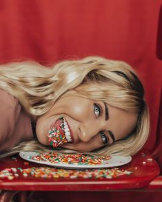 a woman laying on a red chair with a plate full of sprinkles