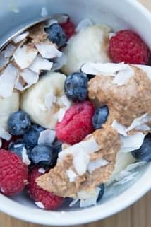 a bowl filled with fruit and granola on top of a wooden table