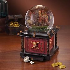 a snow globe sitting on top of a wooden table next to gold coins and other items