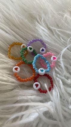 five bracelets with beads and eyeballs are on a white fur surface, one is in the shape of an eyeball