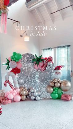 christmas decorations are on display in a room with white walls and ceilings, along with red and green balloons