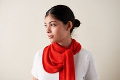 a woman wearing a red scarf standing in front of a white wall