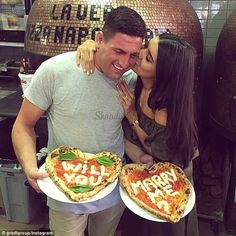 a man and woman holding two pizzas with the words i love you written on them