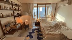 a bed room with a neatly made bed next to a window and a shelf on the wall