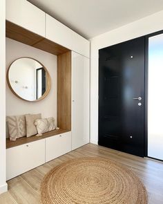 a room with a round rug, mirror and black door