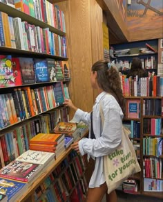 a woman is looking at books in a library