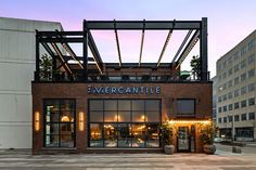 the entrance to an outdoor restaurant with lights on it's windows and brick facade