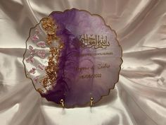 a purple and gold plate sitting on top of a white cloth