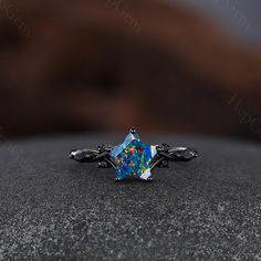 a ring with an opal colored stone in the center on top of a rock