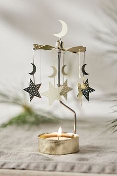 a candle holder with stars and moon hanging from it's sides on a table