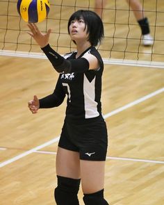 a woman in black and white uniform playing volleyball