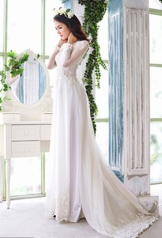 a woman in a white wedding dress standing next to a mirror