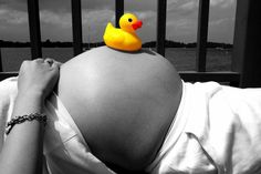 a pregnant woman with a rubber ducky on her head is looking at the water