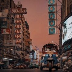 an old bus driving down the street in front of tall buildings with signs on them