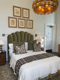 a bedroom with a bed, lamps and pictures on the wall above it's headboard