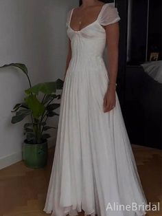 a woman wearing a white dress standing in a room