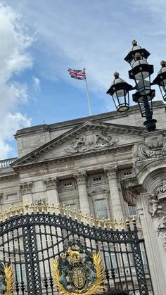 an iron gate with the british flag flying in the background on top of a building