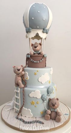 a three tiered cake with teddy bears on top and an air balloon in the middle