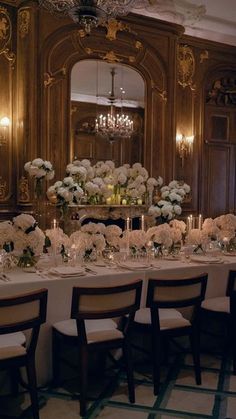 a long table is set with white flowers and candles for a formal dinner or reception