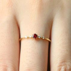 a woman's hand wearing a gold ring with two red stones on the band