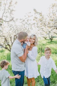 a family poses for a photo in an apple orchard with their two children and one adult