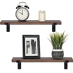 two wooden shelves with pictures and an alarm clock on one shelf next to a potted plant