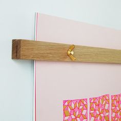 a piece of wood mounted to the side of a wall with pink and yellow designs on it