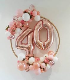 the balloon number forty sits in front of a white wall with pink flowers and balloons