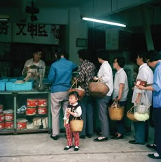 a group of people standing next to each other in front of a store filled with food