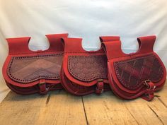 three red leather bags sitting on top of a wooden floor