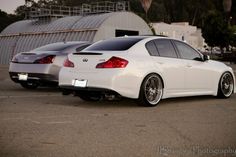 two white cars parked next to each other in a parking lot near a metal structure