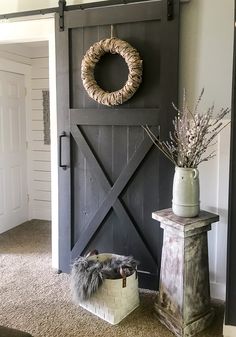 a barn door with a wreath on the wall and a basket in front of it