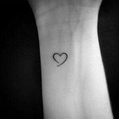 a black and white photo of a small heart tattoo on the left inner wrist,