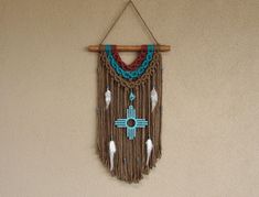 a wall hanging with beads and feathers on it