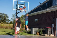 two young men playing basketball in front of a house