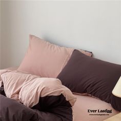 a bed with pink and brown pillows on it