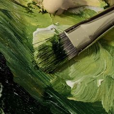 a brush is sitting on top of some green and white paintbrushes that have been painted