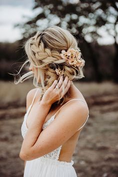 a woman in a white dress is holding her hair up and looking at the camera