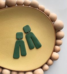 two green earrings sitting on top of a wooden tray next to beads and wood circles