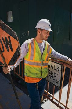 a construction worker standing next to a walk sign