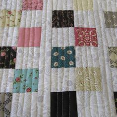 a close up of a quilt made with different colored squares and flowered designs on it