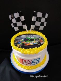 a racing car cake with yellow frosting and checkered flags on top is ready to be eaten