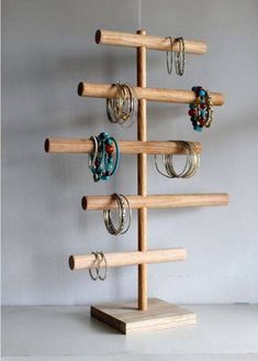 a wooden rack with rings on it and two pairs of earrings hanging from the top