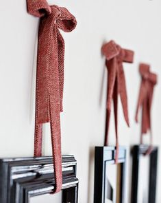 three framed pictures with red bows hanging on the wall next to each other in front of a white wall