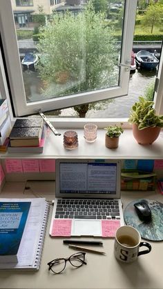 a laptop computer sitting on top of a desk next to a window